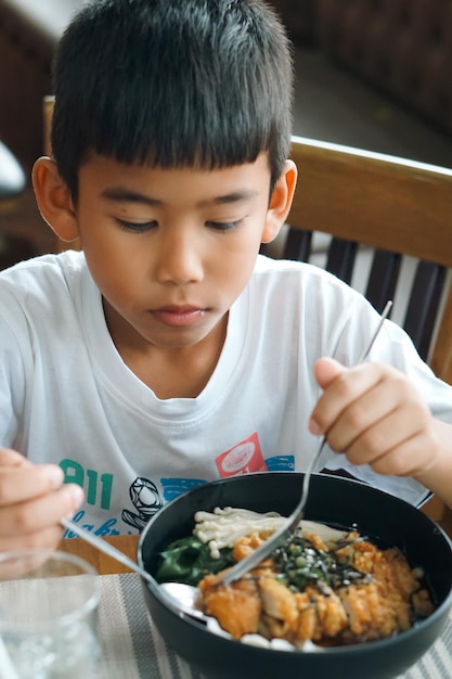 El niño comiendo comida japonesa.