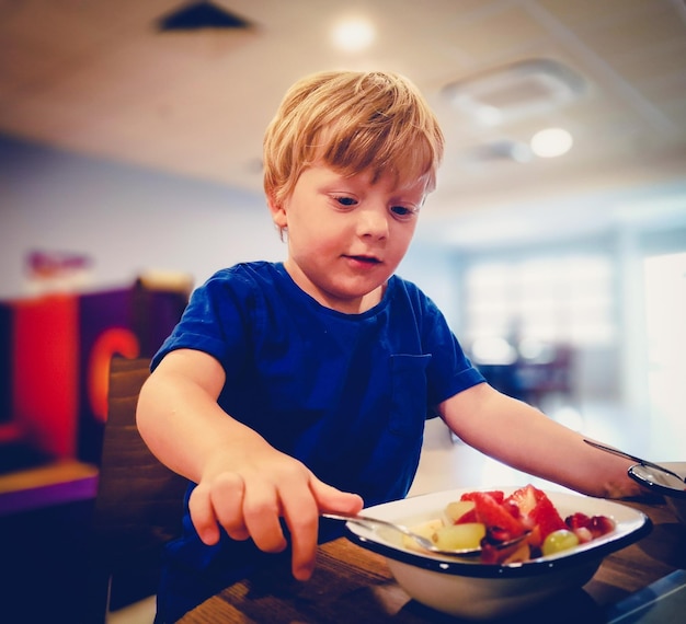 Niño comiendo fruta en la mesa