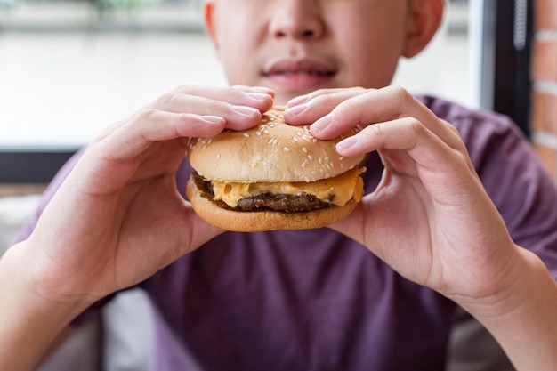 Un niño comiendo una hamburguesa.