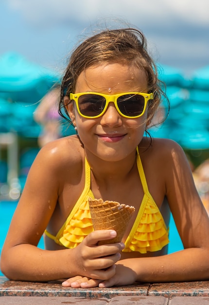 Foto el niño está comiendo helado cerca de la piscina. enfoque selectivo. niño.