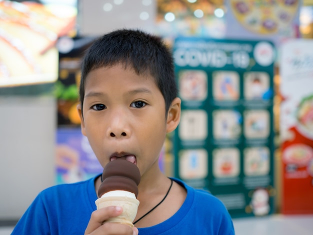 Un niño comiendo helado dentro de un centro comercial.