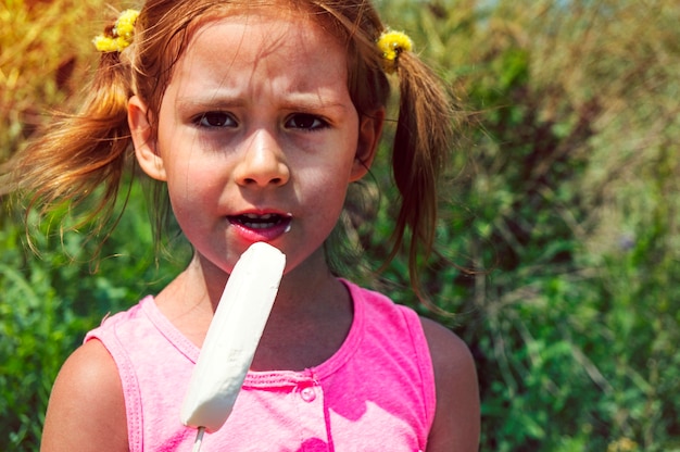 Niño comiendo helado de vainilla. Los niños juegan al aire libre disfrutando de un refrigerio dulce en un caluroso día de verano.