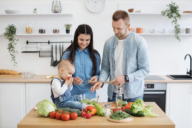 Foto niño comiendo jugoso tomate del tazón en la mesa de la cocina