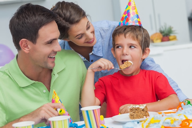 Niño comiendo un pastel de cumpleaños con los padres