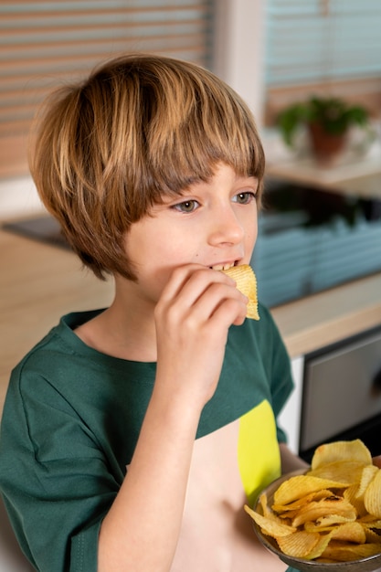 Niño comiendo patatas fritas en casa