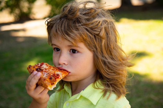 Niño comiendo pizza. El placer del niño y le da un mordisco a la pizza.