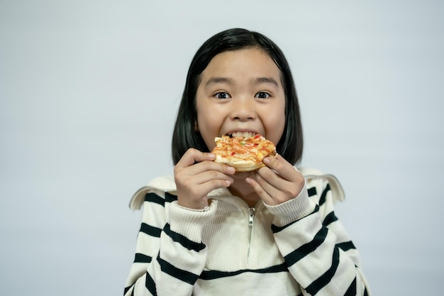 Niño comiendo pizza sobre fondo blanco.