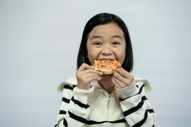 Niño comiendo pizza sobre fondo blanco.