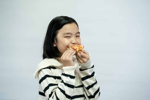 Niño comiendo pizza sobre fondo blanco.