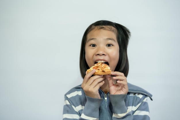 Niño comiendo pizza sobre fondo blanco.