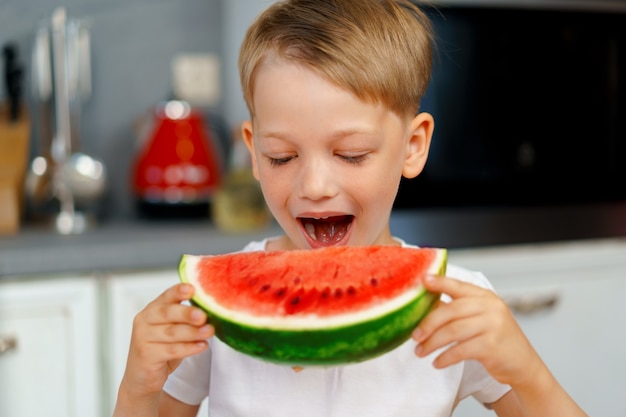 Foto niño comiendo sandía en la cocina