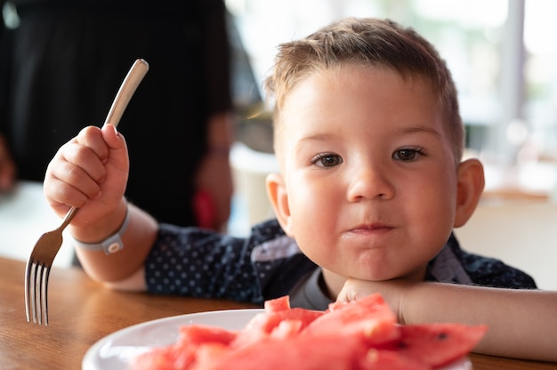 Niño comiendo sandía en un restaurante.