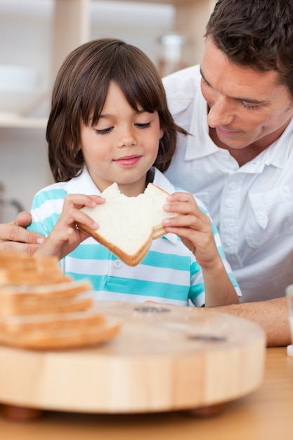 Foto niño comiendo un sándwich con su padre