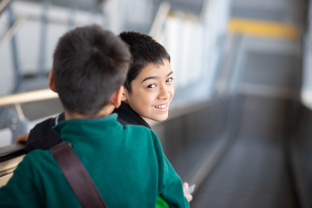 Niño comprando boleto eléctrico y caminando en la estación de tren público con la familia