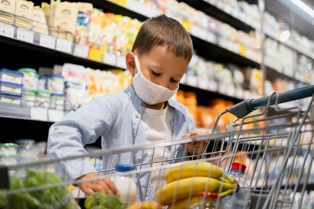 Foto niño de compras con máscaras