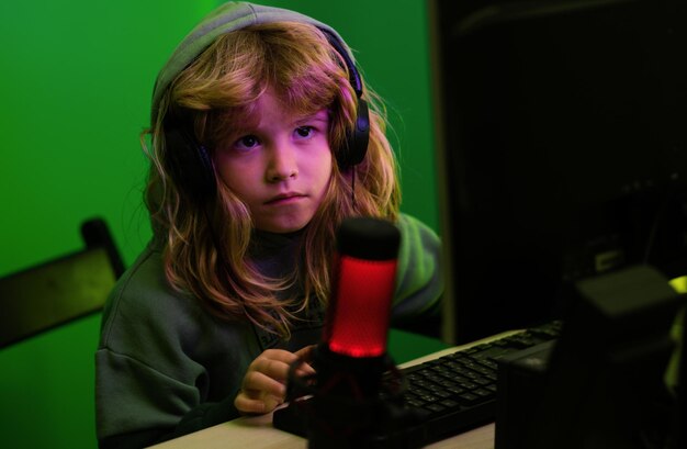 Niño con computadora por la noche Uso excesivo y adicción niños de aparatos Niño pequeño usando computadora de escritorio por la noche Niño niño iluminado por la luz azul de una pantalla de computadora