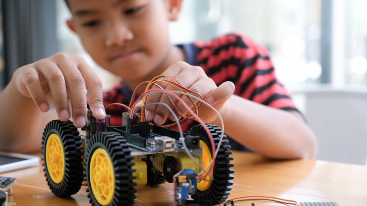 Foto niño concentrado creando robot en el laboratorio.