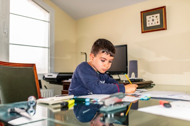 Niño concentrado haciendo los deberes en la oficina de papá