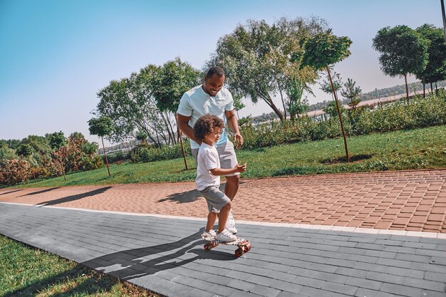 Niño concentrado patinando afuera en el parque con su padre