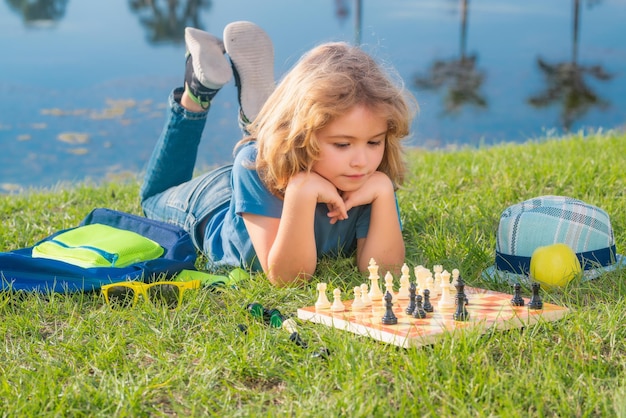 Niño concentrado y pensante inteligente jugando al ajedrez al aire libre en el parque