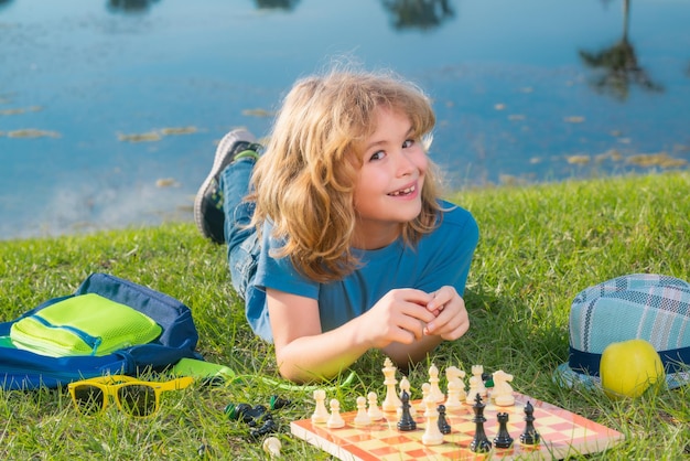 Niño concentrado y pensante inteligente jugando al ajedrez al aire libre en el parque