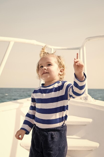 Foto niño concepto marinero niño niño viajar en barco en el mar niño pequeño mantener el dedo índice levantado mira allí