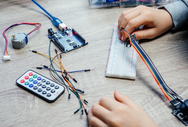 Un niño conecta cables a chips de sensores mientras aprende codificación y robótica arduino