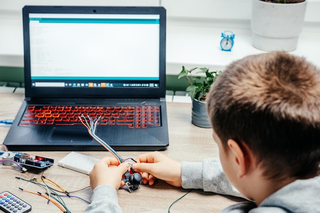 Un niño conectando cables a chips de sensores mientras aprende codificación arduino y robótica
