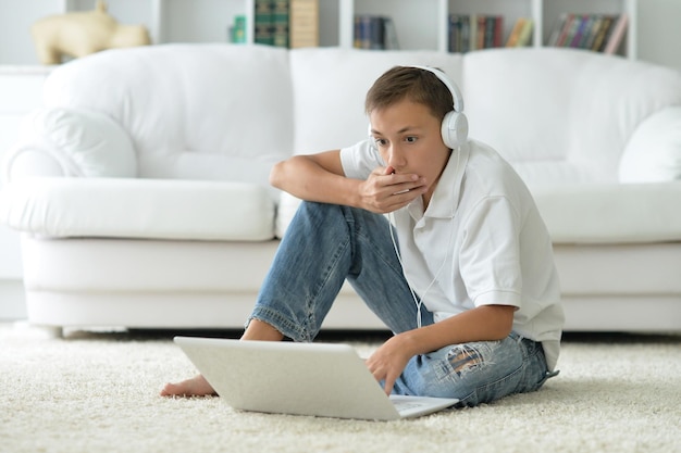 Niño confundido en auriculares usando laptop en la habitación