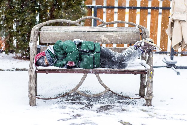 Un niño congelado duerme solo en un banco sobre un fondo de nieve