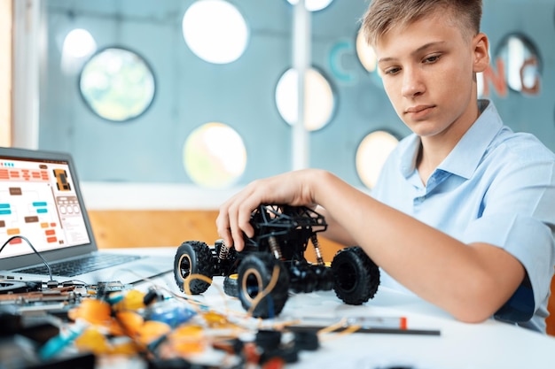 Foto niño considera partes de automóviles robóticos mientras aprende en la clase de stem edificación