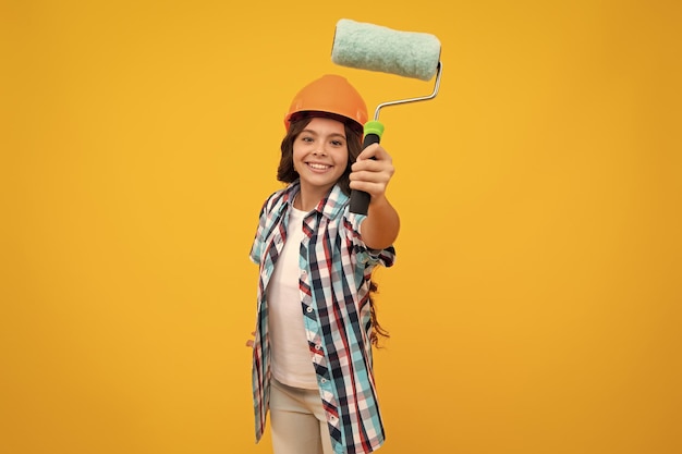 Niño constructor con casco de casco adolescente pintora con herramienta de pincel de pintura o rodillo de pintura