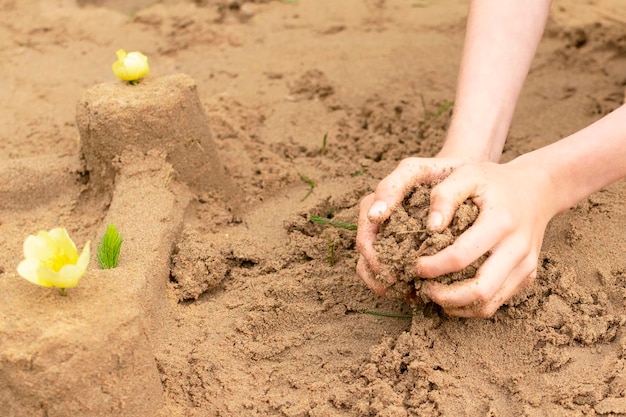 Un niño construye castillos de arena en la playa en verano Paseo marítimo Las manos del niño en la arena Entretenimiento al aire librexA