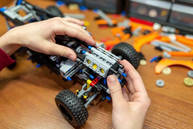 Niño construyendo un coche robot con un constructor electrónico Niño aprendiendo conceptos básicos de ingeniería jugando con un constructor tecnológico moderno