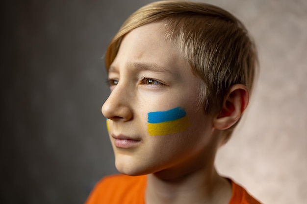 Un niño contra la guerra un niño orgulloso con una bandera pintada de Ucrania en sus mejillas