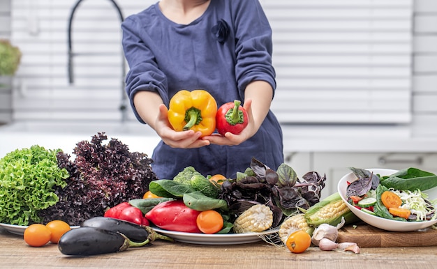 Un niño contra la pared de una variedad de verduras en el proceso de preparar una ensalada.