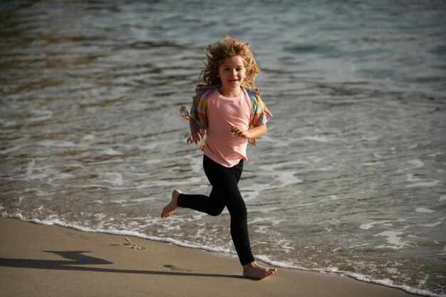 Niño corriendo por el agua cerca de la orilla a lo largo de la playa del mar Un niño corre a lo largo de la costa del mar Resto de niños en vacaciones de verano Pequeño atleta en entrenamiento Corredor haciendo ejercicio para correr para niños