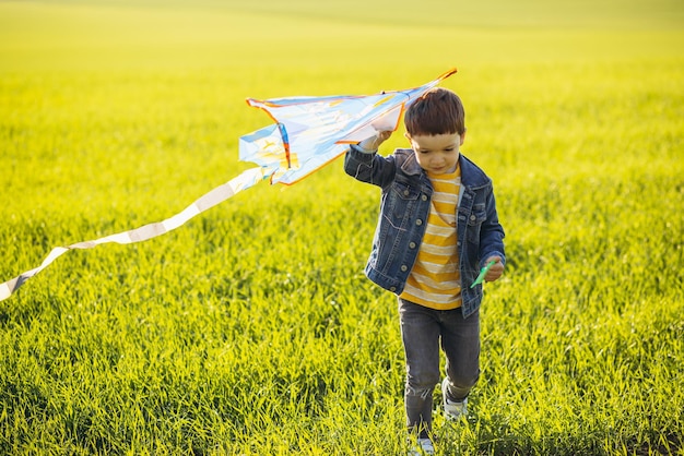 Foto niño corriendo en el campo con cometa