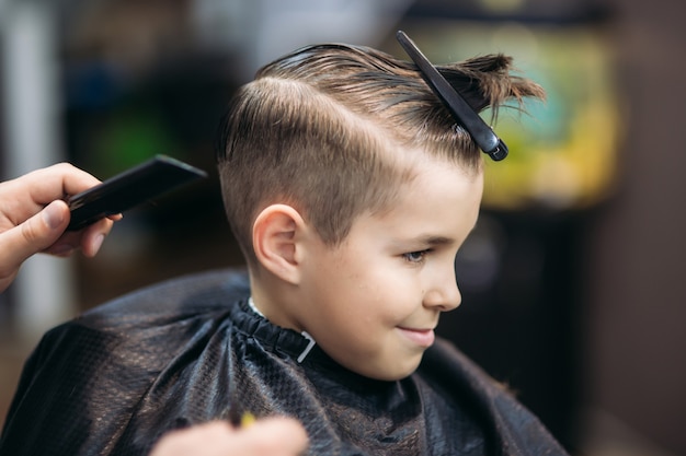 Niño en un corte de pelo en la peluquería se sienta en una silla