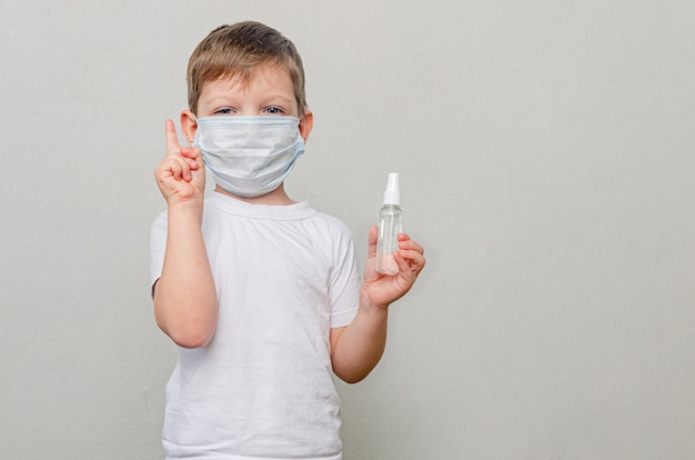 Niño en cuarentena debido a una pandemia (epidemia) del coronavirus. Un niño con una máscara médica protectora tiene un desinfectante en sus manos.