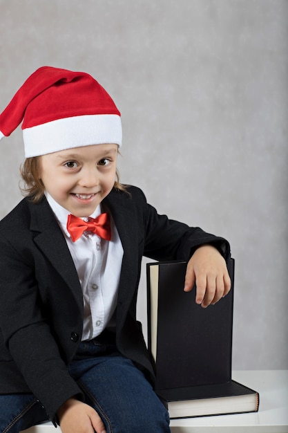 Niño de cuatro años con sombrero de Papá Noel y chaqueta clásica negra. De cerca