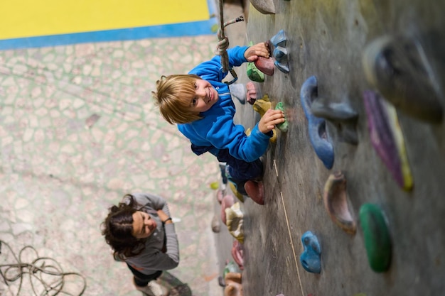 Foto niño de cuatro años sube la pared de escalada en el pasillo