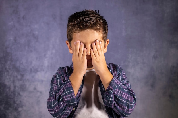 Foto niño cubriendo la cara con las manos