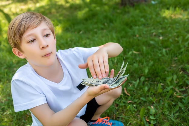 Un niño en cuclillas sosteniendo billetes de un dólar frente a él los empuja hacia adelante de una pila