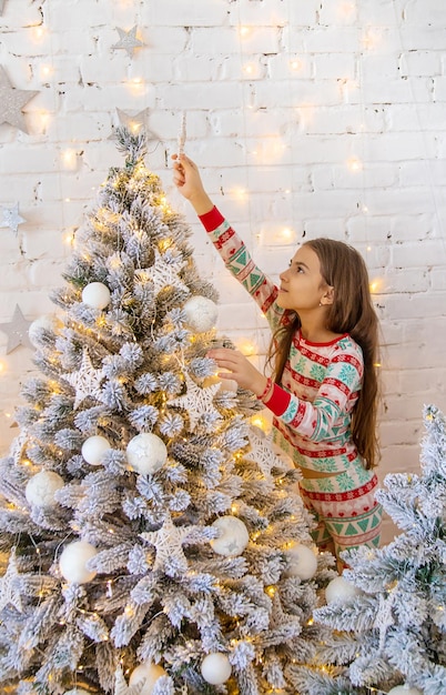 Un niño cuelga una estrella en un árbol de Navidad Enfoque selectivo