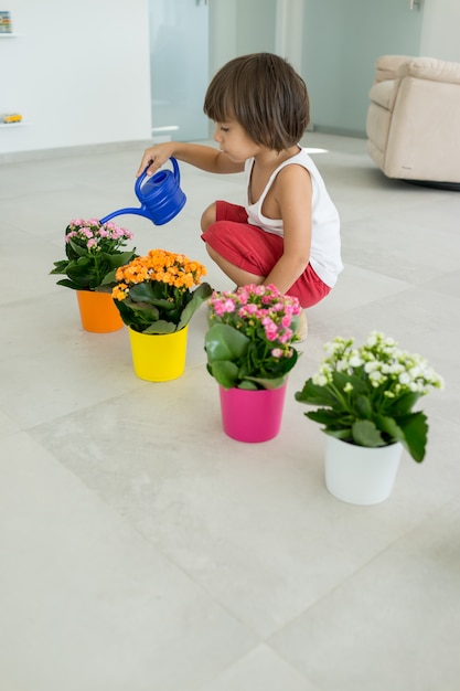 Niño cuidando plantas y flores en casa