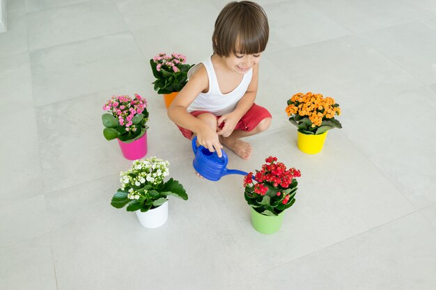 Niño cuidando plantas y flores en casa
