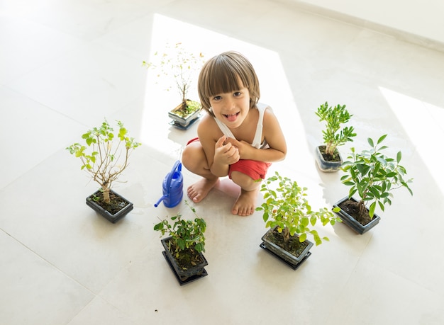 Niño cuidando plantas y flores en casa