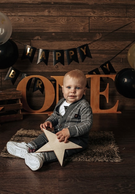 Un niño de cumpleaños en un traje se sienta sobre un fondo marrón con una decoración