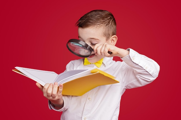 Niño curioso leyendo un libro a través de una lupa